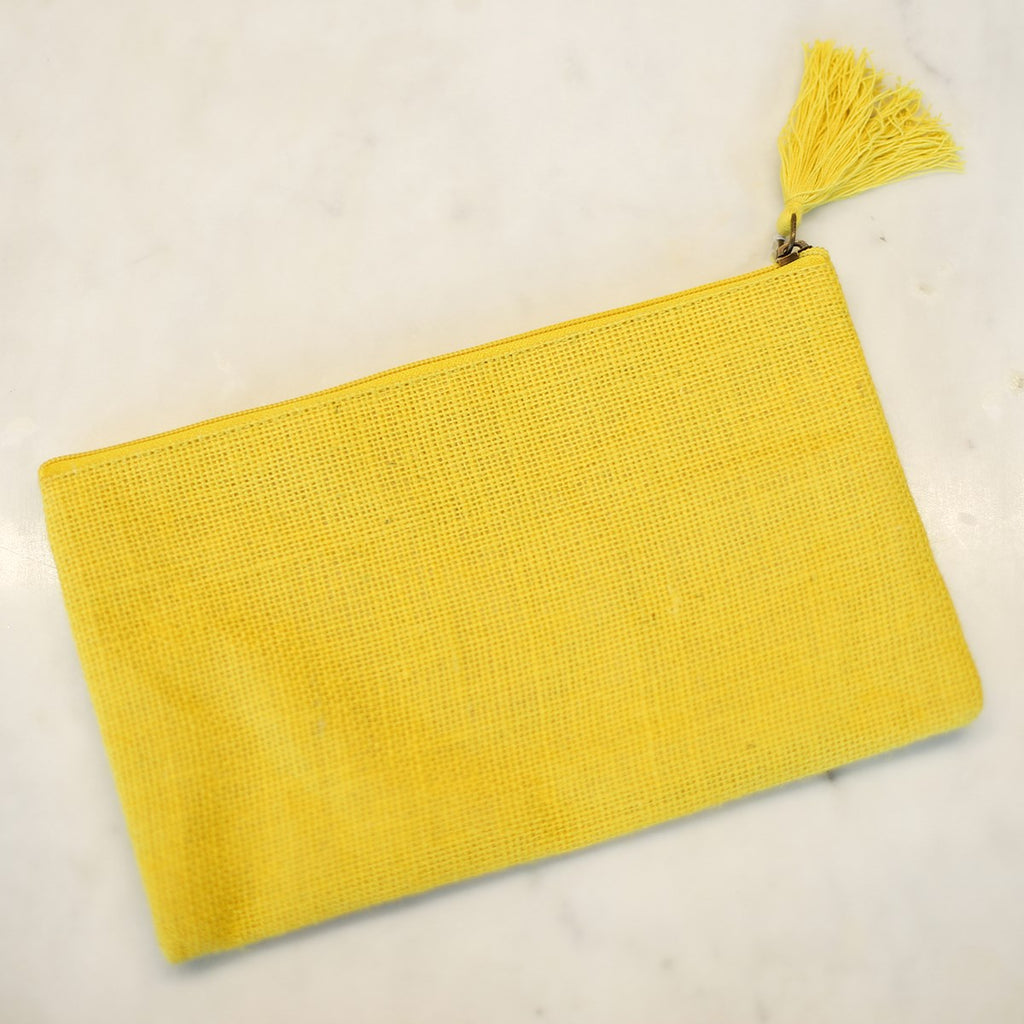 A lemon yellow jute cosmetic bag with a yellow tassel attached to the zipper.