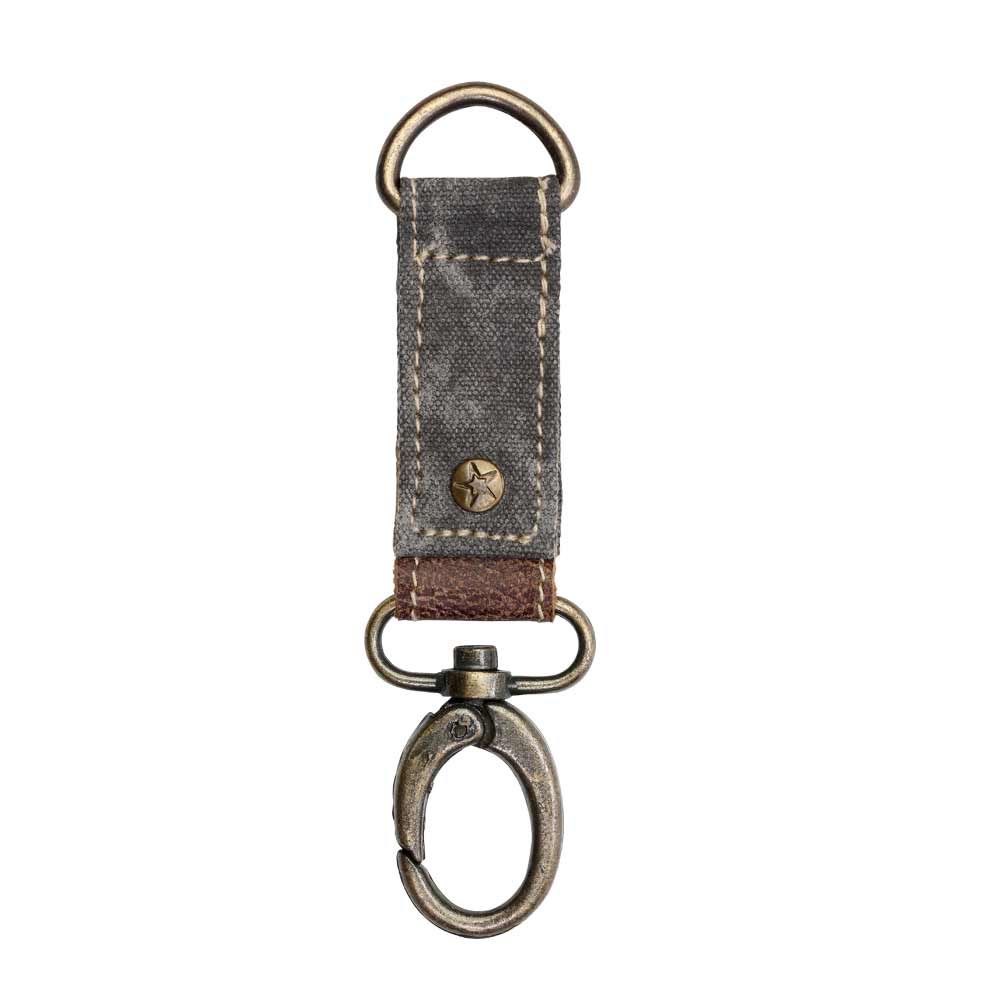 Canvas key fob with brass details, leather accent, and a rivet with a star embossed.  The canvas color is black.