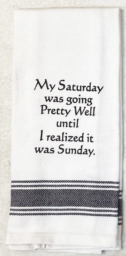 White flour sack tea towel with black printed lettering that reads "My Saturday was going Pretty Well until I realized it was Sunday."