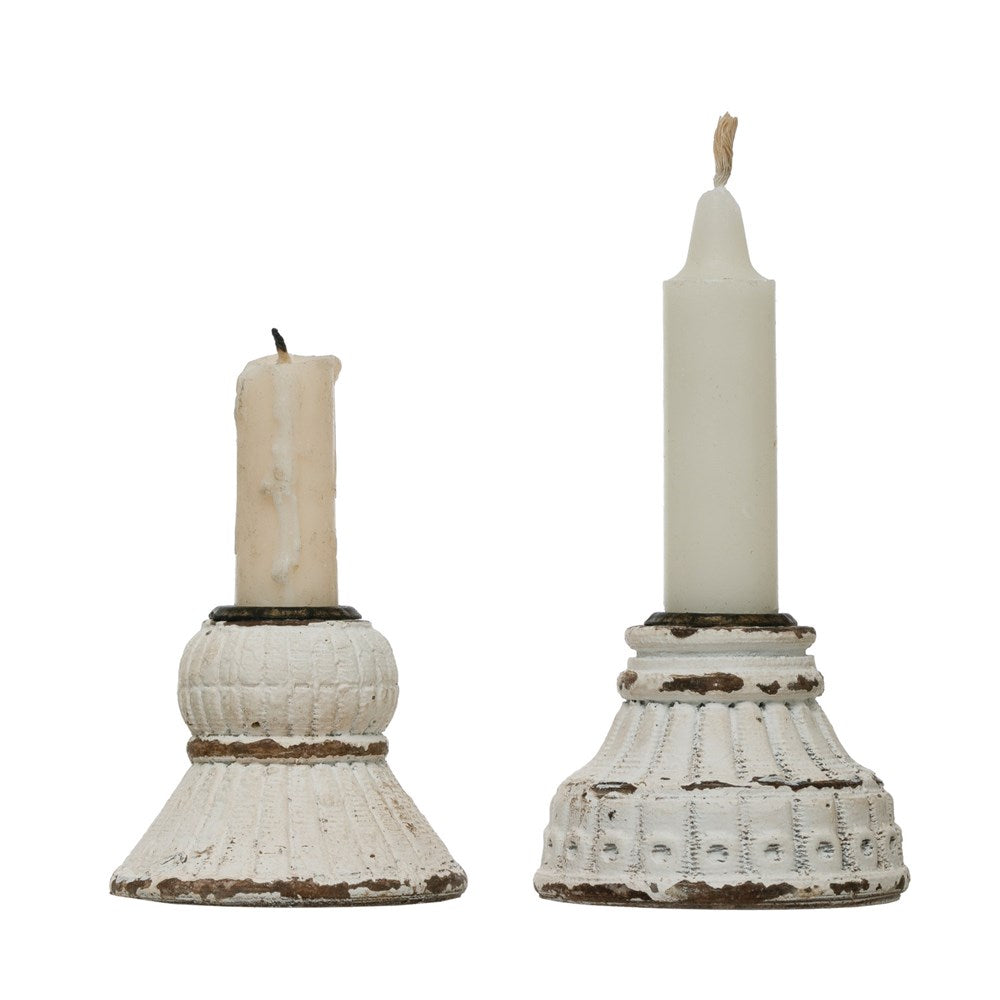 Two taper candle holders on a white background.  Each has a flat white finish, and dark copper detail around the candle, with artistic chipped detail around the rims.  The one on the left has a rounded top and flared bottom.  The one on the right has a fluted detail and tapers down from the candle.