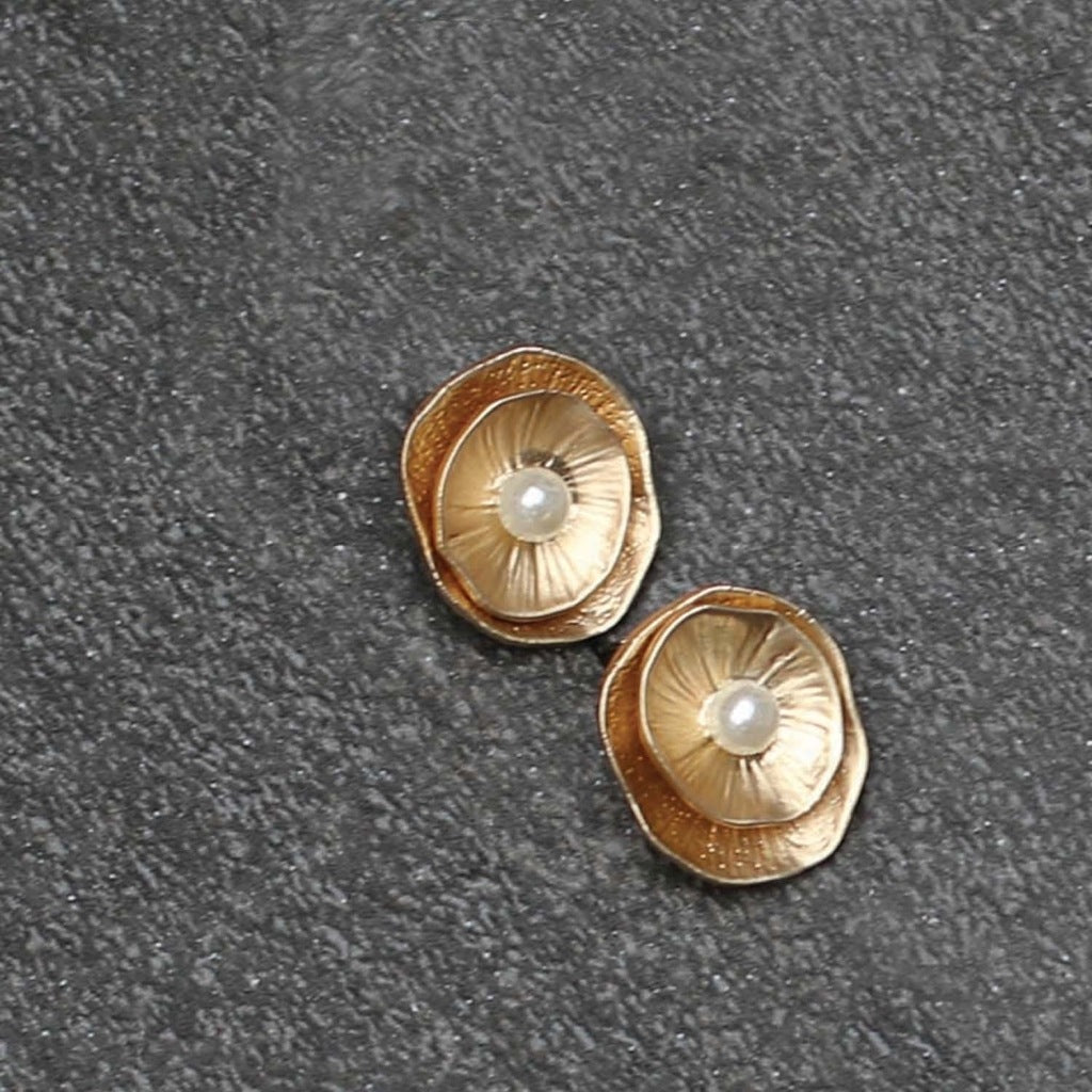 A pair of gold earrings, each feature a pair of layered gold concave pieces with a pearl detail in the middle.