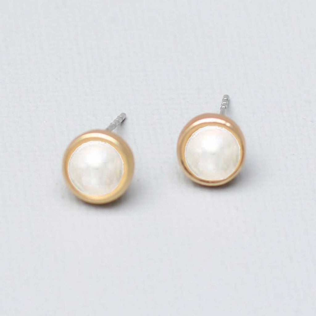 A pair of stud earrings.  A pearl center surrounded by a thin band of gold.