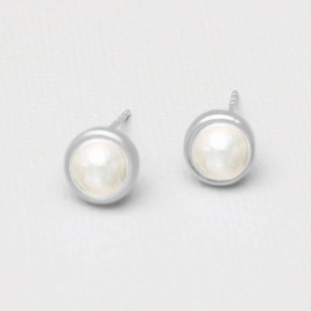 A pair of stud earrings.  A pearl center surrounded by a thin band of silver.