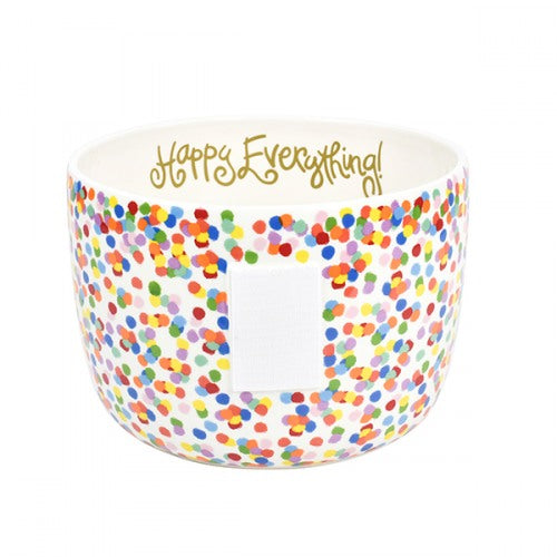 A deep bowl with a confetti pattern around the outside, and a plain white inside.  Happy Everything! is written just under the rim of the inside in gold script.  A piece of velcro is on the outside of the bowl to receive attachments.