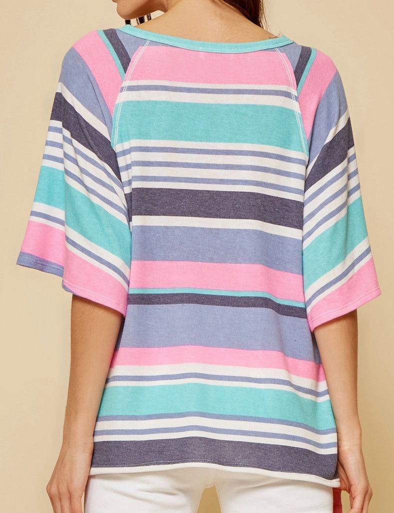 Back view of model wearing a slightly oversized striped top.  Top has alternating thin and thick stripes in pink, teal, gray, purple and white.