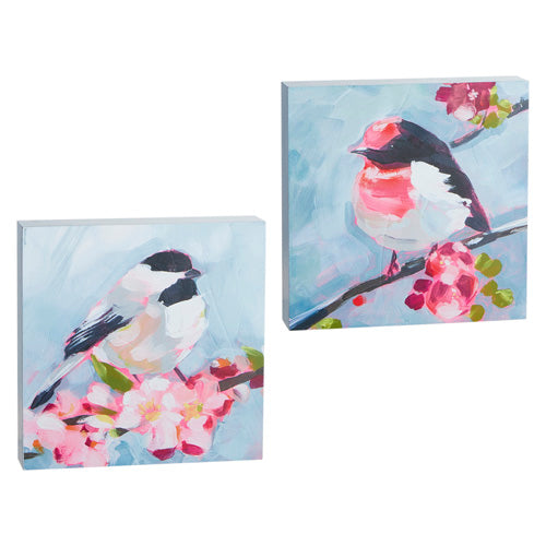 A pair of prints on thick wooden blocks.  Each print shows a bird in a brushstroke style of painting, sitting on a spring blossom branch.  One bird is white with black features, and the other bird has a touch of red/pink on its head and chest.