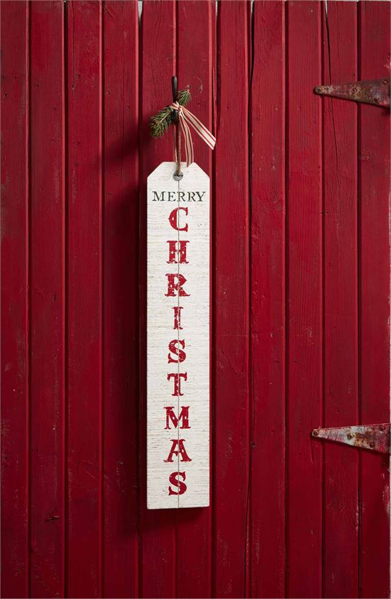 Back of 'Welcome' Sign, wooden distressed white washed sign with jute loop at the top for hanging.  'Merry Christmas' is written horizontally in dark green text above 'Christmas' which is lettered vertically in a red font.  Sign is hung from a nail on a red slatted wooden door.