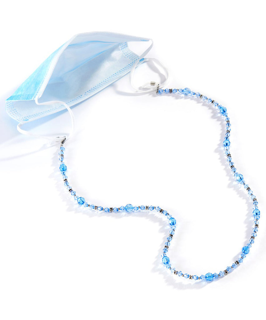 An image of a blue crystal beaded lanyard attached to a light blue medical mask.  The mask is in the upper left hand corner, and the lanyard cascades away from it towards the viewer.