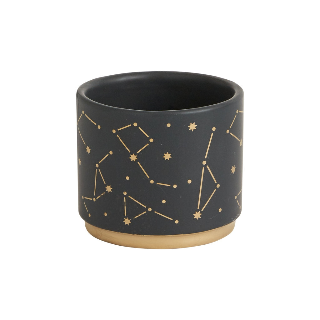 A cylindrical pot on a white background.  It is dark gray with a series of constellations and stars painted on it in gold.  The base of the pot is also a ring of metallic gold.