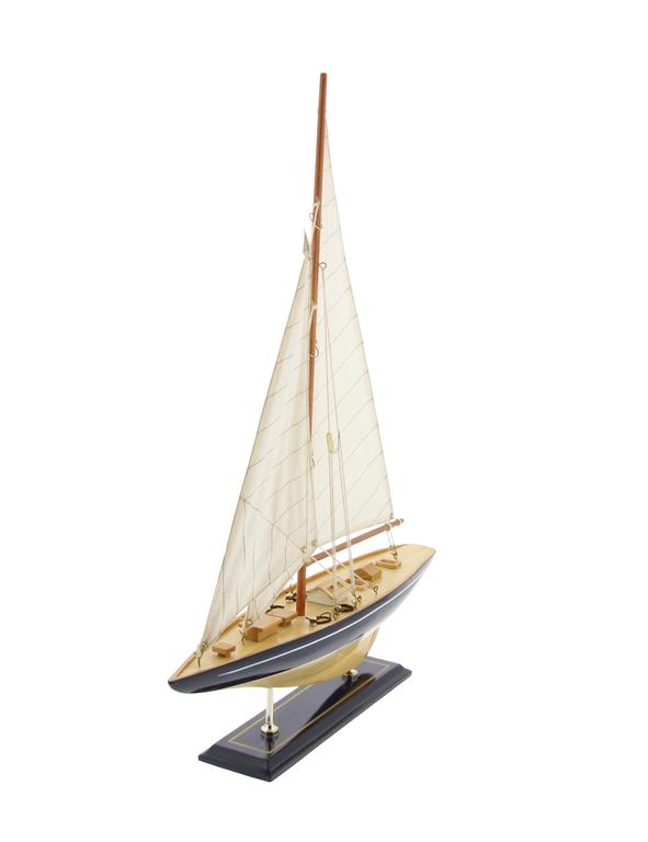 An image from an angle of the front and side of a wooden model sailboat.  The base is dark brown and has two vertical bras supports holding the hull of the boat.  The boat itself has a wide navy stripe running the length of the boat, and a thin white one just below the railing.  The sails are off white and have a thin pin stripe diagonal navy blue pattern. 