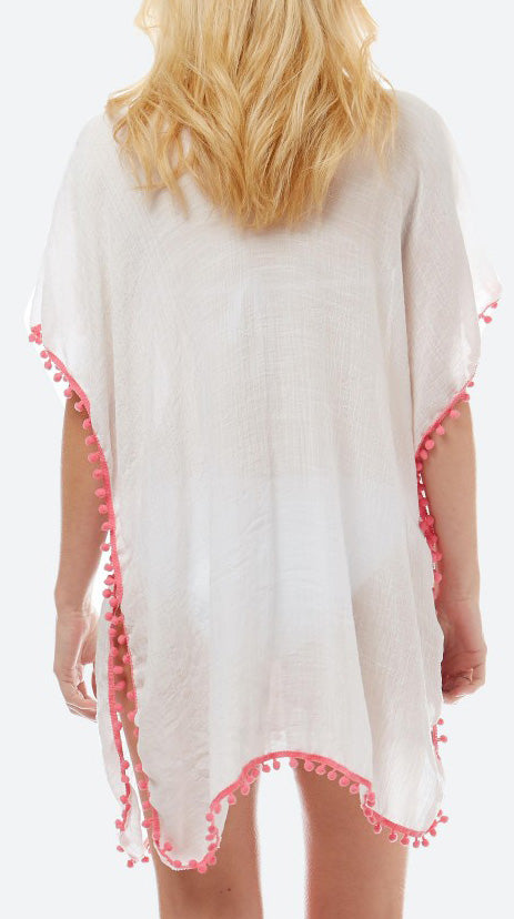 View of the back of a model wearing a loose fitting white top.  The bottom and arm are accented with pink pom pom trim.