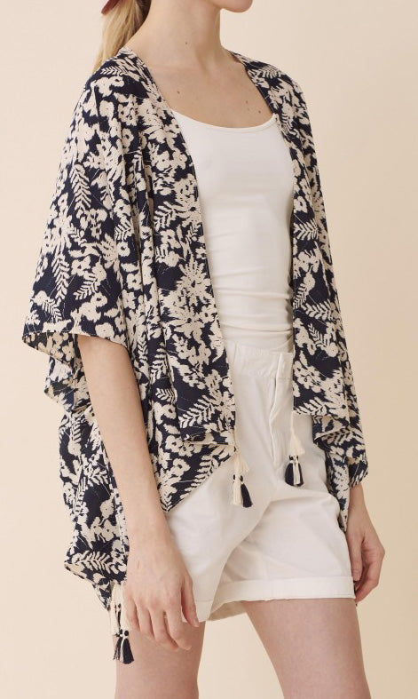 Front view of model wearing a navy and white floral kimono over a white top and shorts.