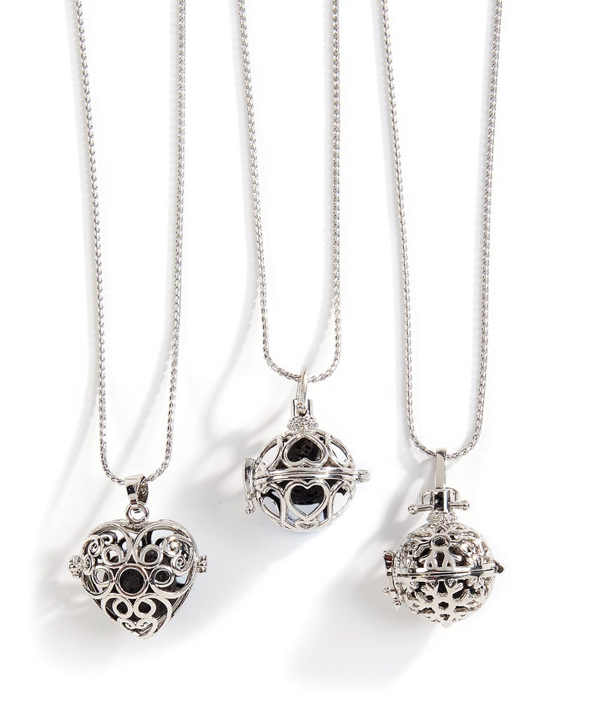 Three silver necklaces each with a different filigree pendant.  The left one is a heart, the center is a sphere with hearts around it, and the third is a floral design.