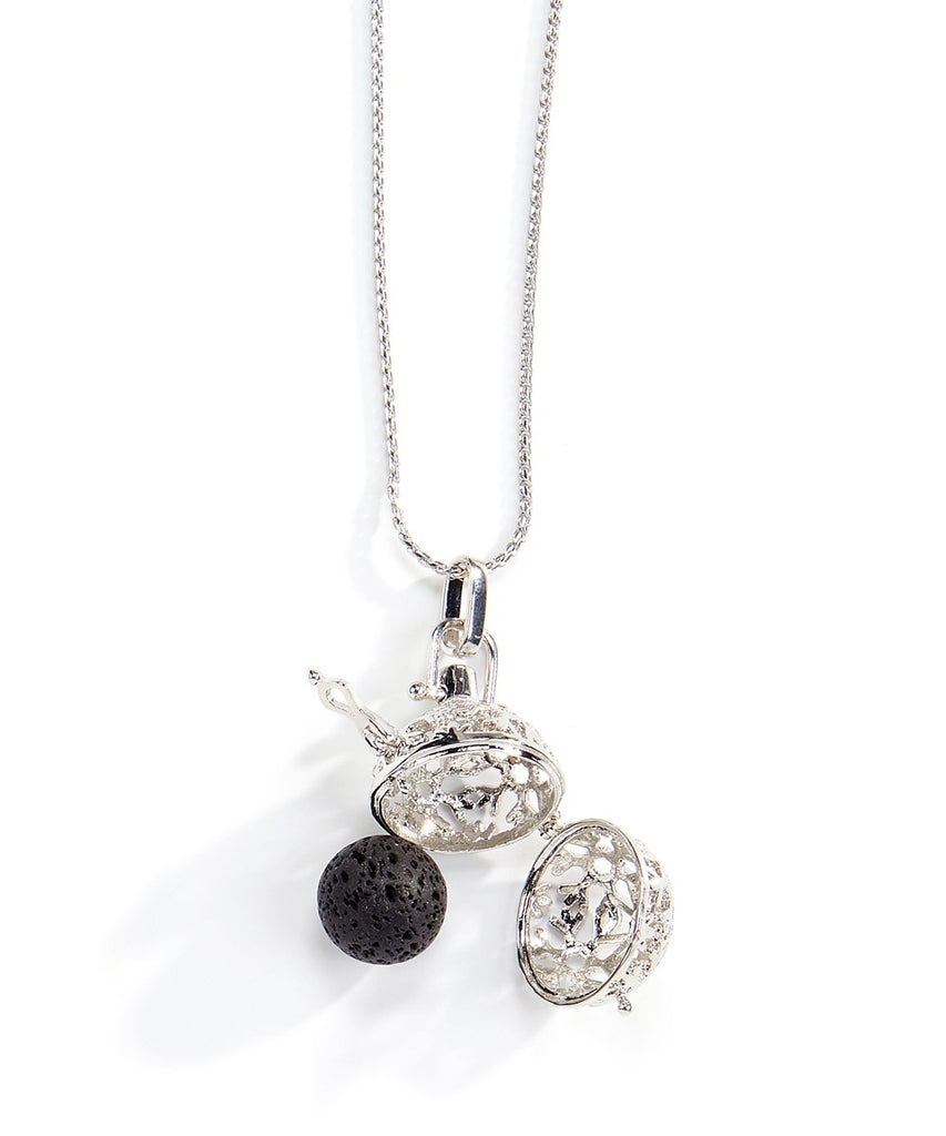 An image of a pendant on a silver chain that is open showing a round lava rock that fits inside the pendant.