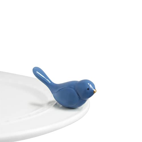A blue bird with gold beak attached to the edge of a tray.