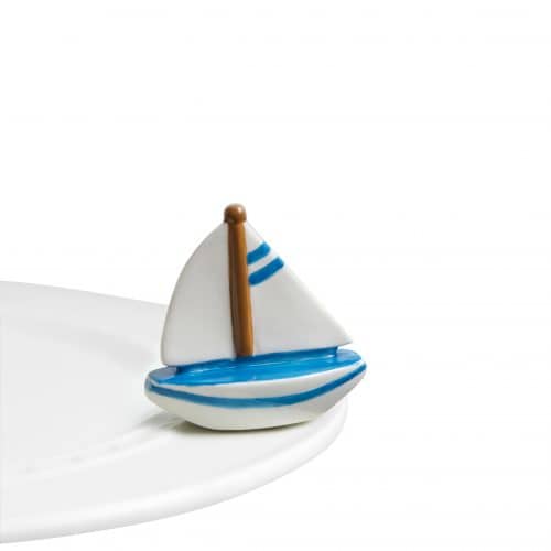 A ceramic sailboat with blue detail, attached to the edge of a ceramic tray.