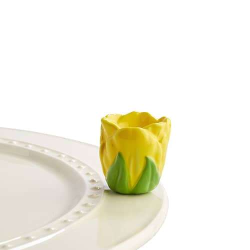 A dimensional yellow ceramic tulip attached to the edge of a tray. 