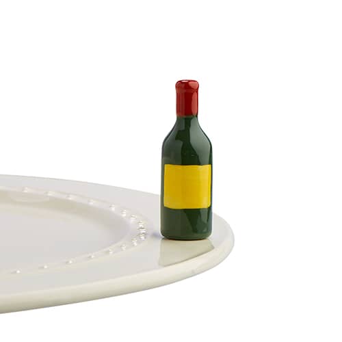 A ceramic wine bottle with blank yellow label attached to the edge of a ceramic tray.