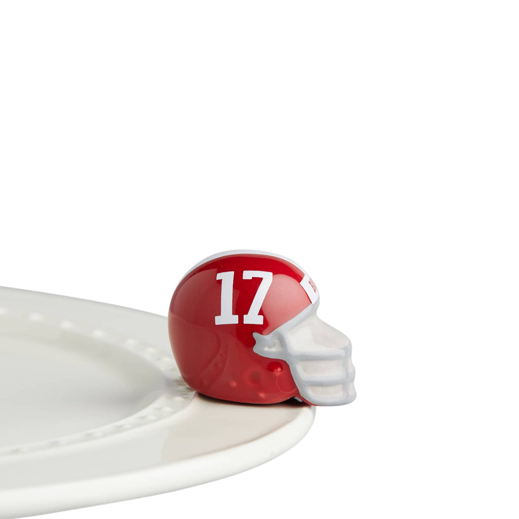 A dark red helmet with the number 17 in white, attached to the edge of a ceramic tray.