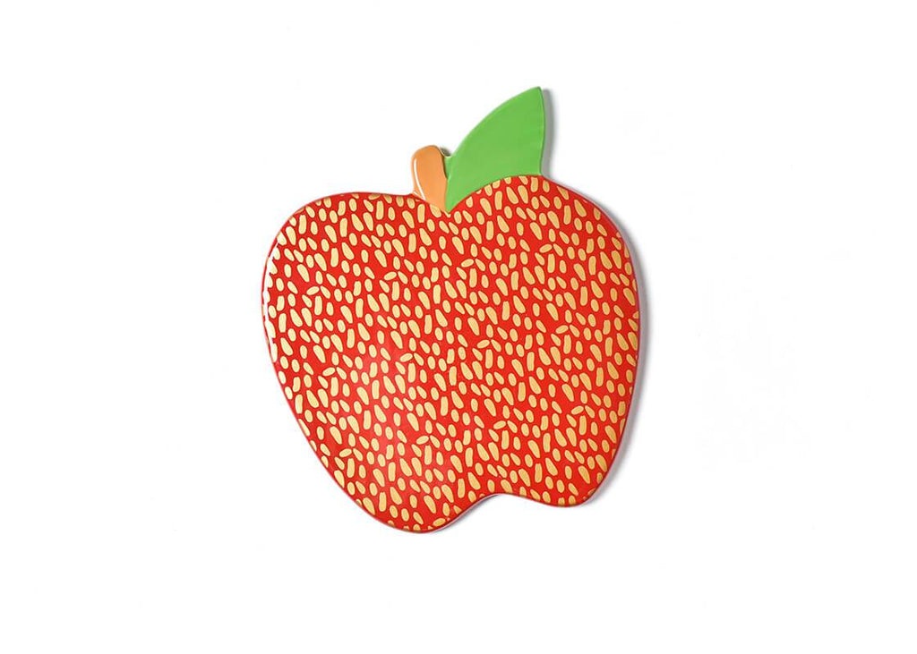 A flat ceramic red apple with green leaf on its stem.  The red portion of the apple has a random gold dot pattern applied all over it.