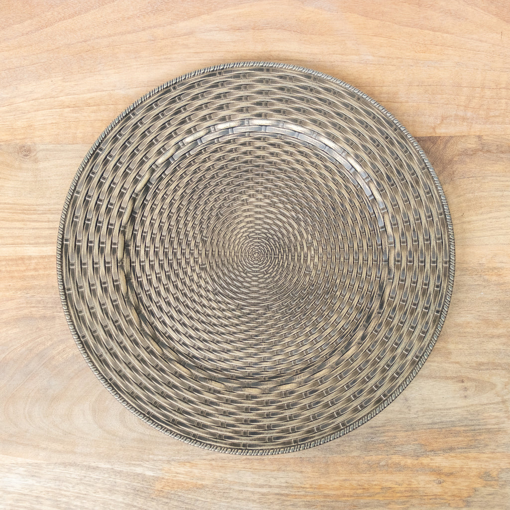 A plastic charger with an embossed basket weave pattern in a circular formation.