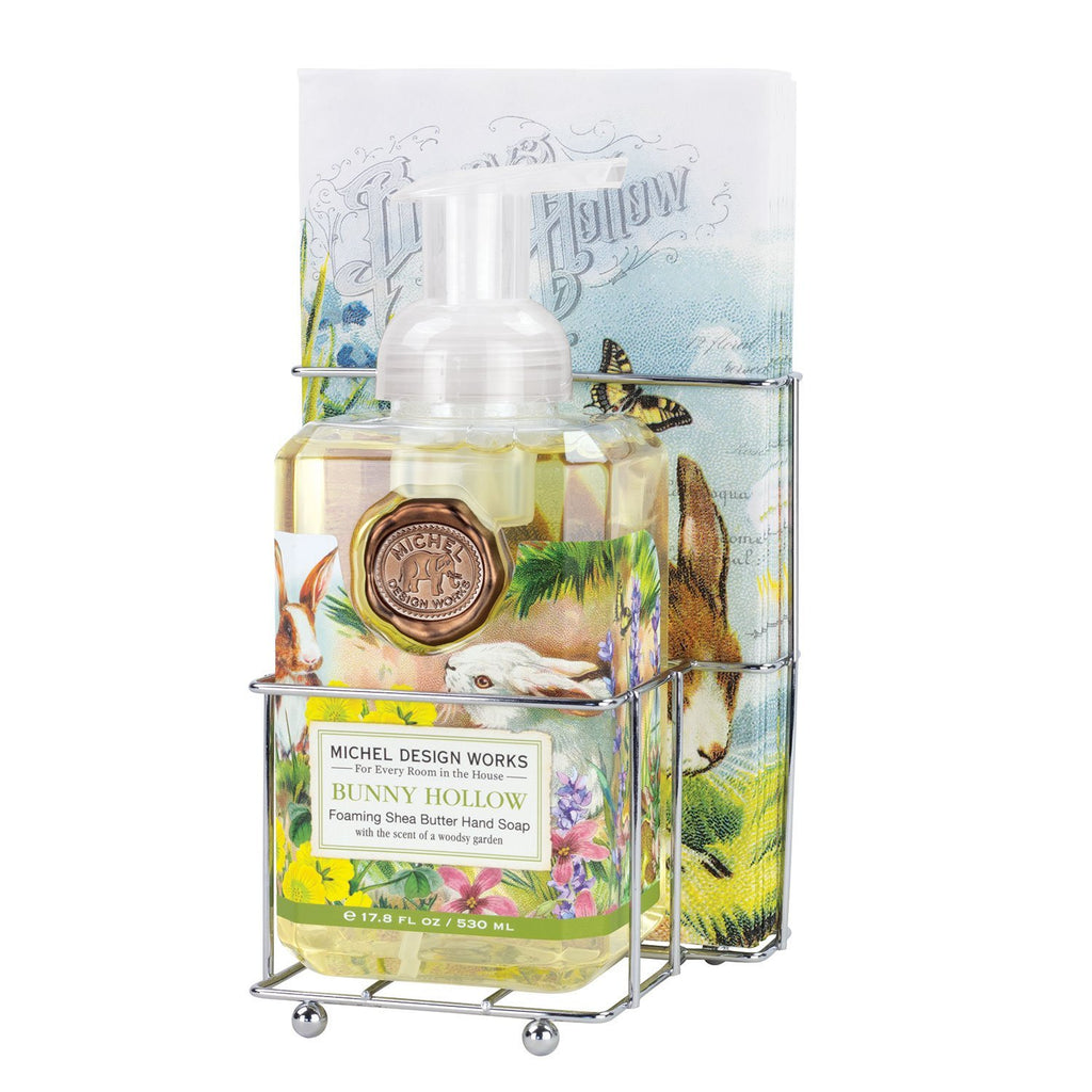 A chrome caddy with coordinating napkins and foaming hand soap.  Images on the label and napkins are of bunnies frolicking in a hollow around spring flowers.