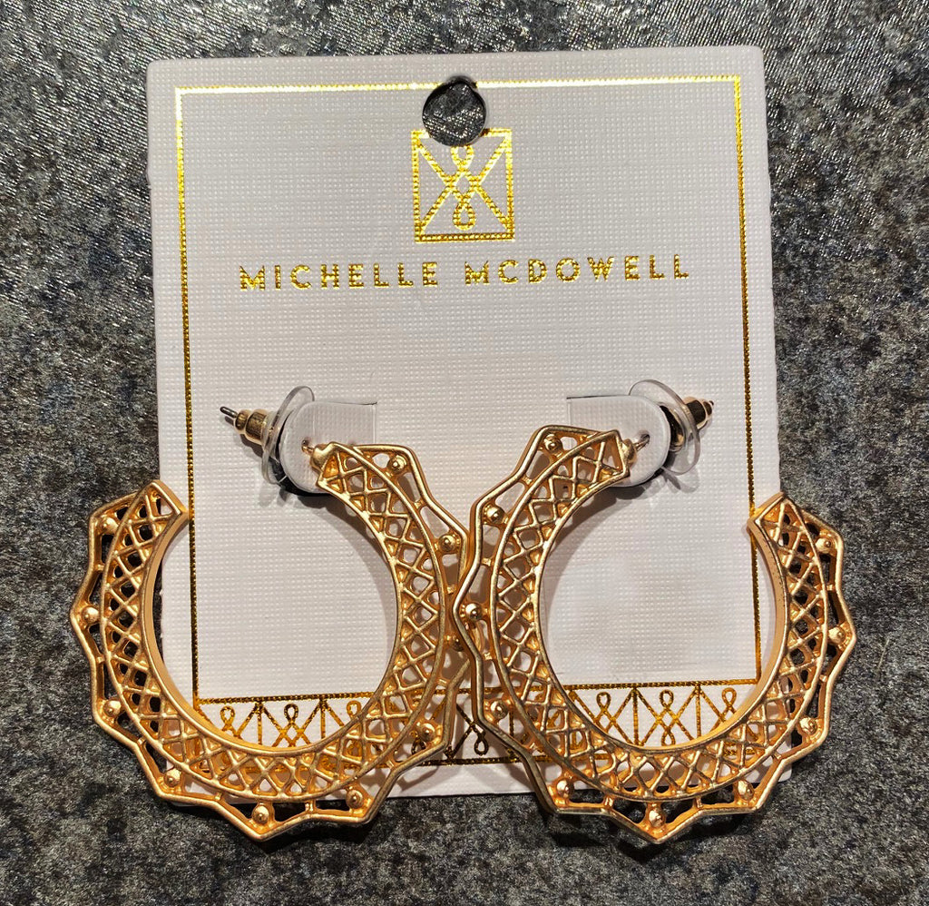 A pair of ornate gold hoops on a display card from Michelle McDowell. 
