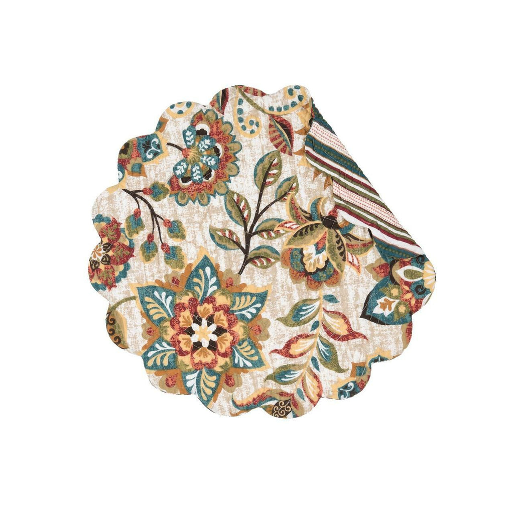A round scalloped quilted placemat on a white background.  The pattern is of flowers and leaves in hues of ochre, tomato, blue, green and brown.  A corner is folded over showing a striped pattern in the same colors as the front.