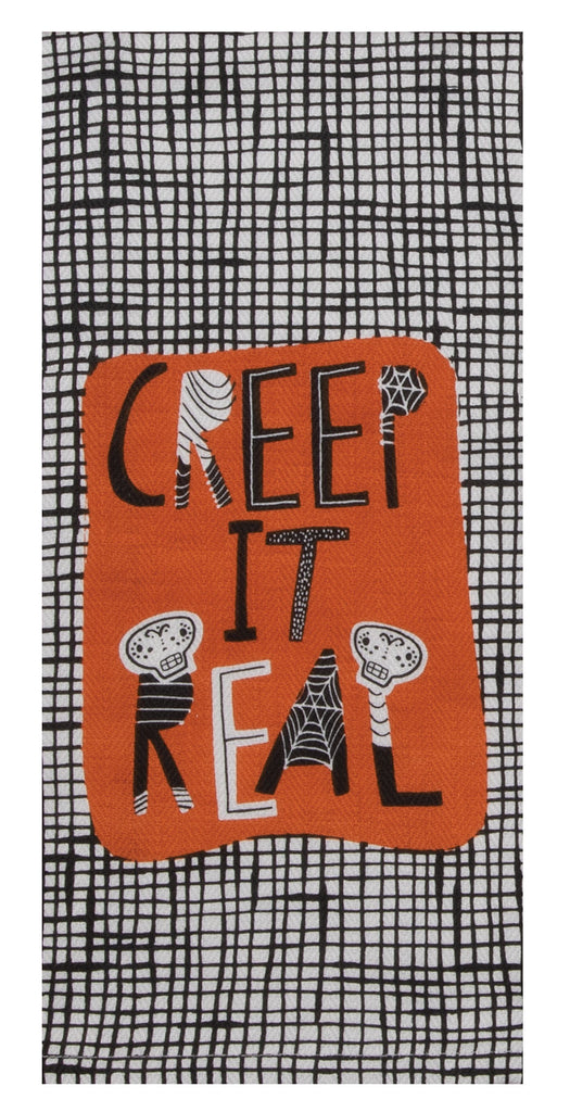 A tea towel on a white background.  The towel has a printed black and white scratch plaid illustrated background.  On top of it is an orange area with funky text that says 'Creep it Real'.  Some of the letters are black, others black and white, and others have candy skulls on them.