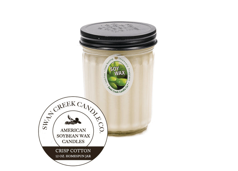 An image of a candle in a glass jar with a black lid.  The candle is white.  A graphic seal in front of the candle says 'Swan Creek Candle Co. American Soybean Wax Candles Crisp Cotton 12 oz. Homespun Jar'.  The candle also has an ovular white label attached by a string wrapped under the lid.  The label has an image of green soybeans and says 'Soy Wax' along with 'Lead Free, intensely fragrant, clean burning'
