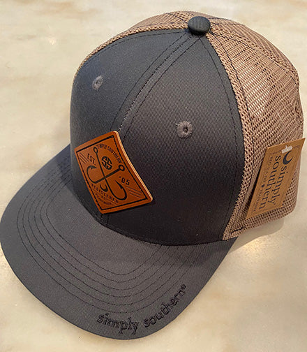 A photo of a baseball cap that has a gray front and a tan mesh back.  On the front of the hat is a diamond shaped leather patch that features a design of two criss crossed fishing hooks above a moon in eclipse.  The text around the hooks says 'Simply Southern SS Ext. '05, Registered Trademark'