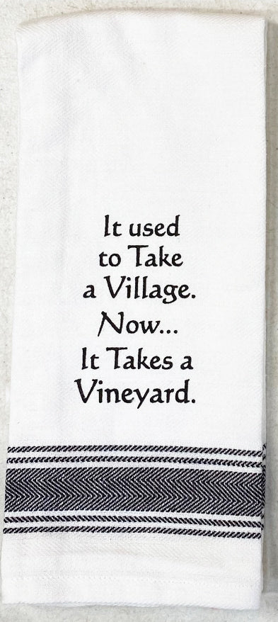 White flour sack tea towel with black printed lettering that reads "It used to Take a Village.  Now...it takes a vineyard."