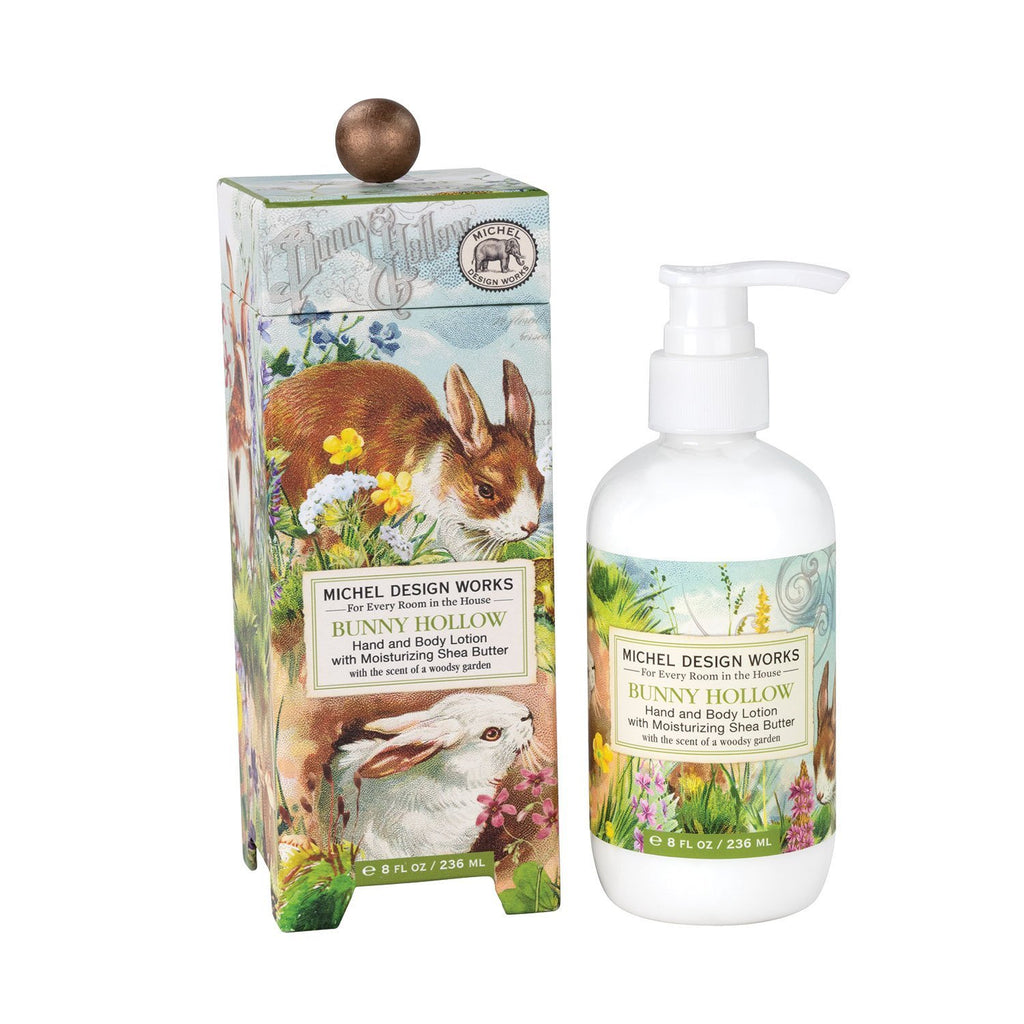 A decorative box with an image of bunnies frolicking in a hollow surrounded by spring flowers next to a bottle of hand and body lotion with a corresponding label.