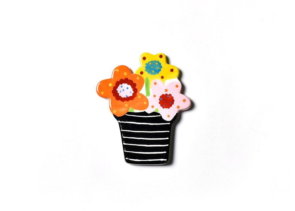 A flat ceramic pot of flowers.  The pot is black with thin white horizontal stripes.  Each of the flowers is orange, yellow and pink, with contrasting polka dots and colorful centers.