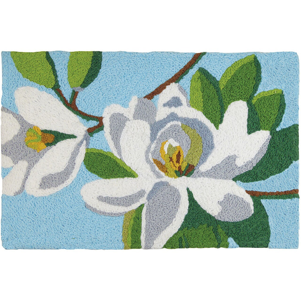 A woven rug with an image of magnolia blossoms on it on a sky blue background.