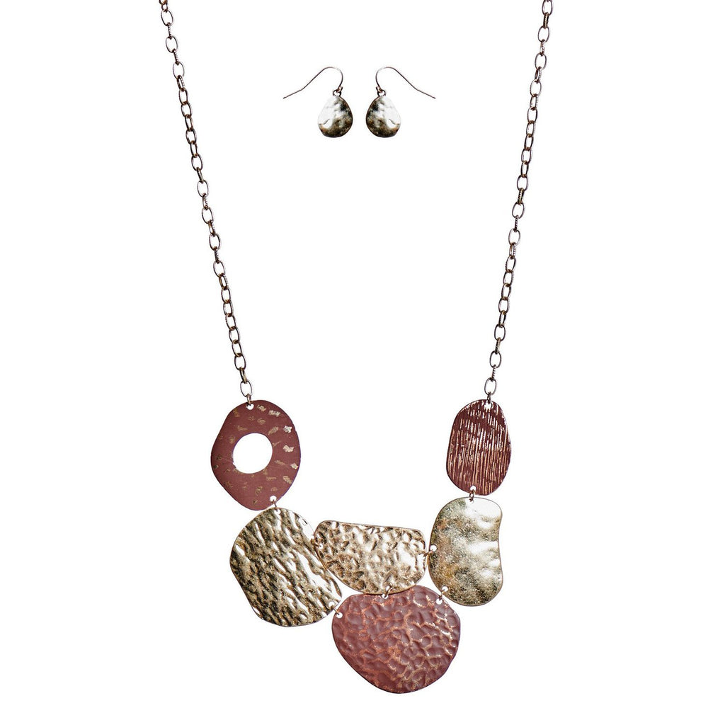 A necklace and earring set.  The earrings are pear shaped and made of a hammered metal.  The necklace is composed of a variety of organic rounded shapes and the textures vary from hammered to striated.  They are of gold, and the ones at the each end and the in the middle have a red wash on them.