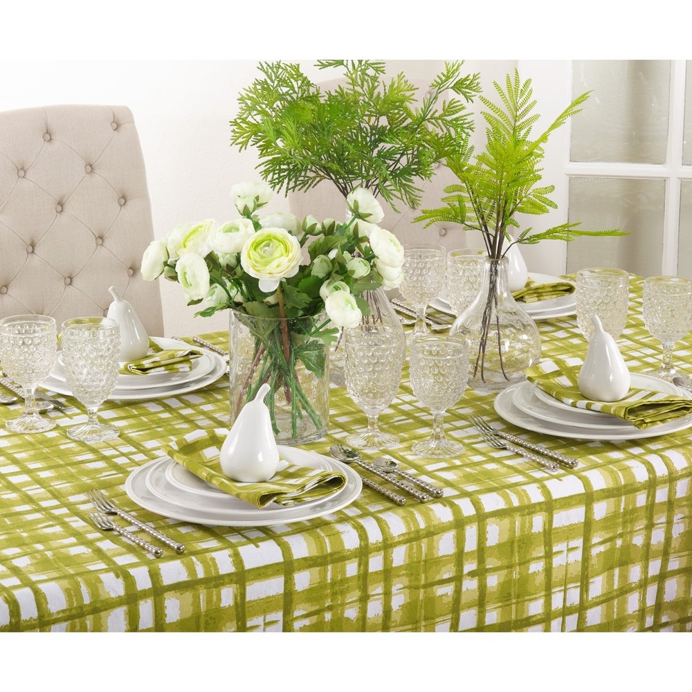 A set table on a white table cloth with green plaid pattern that is reminiscent of a watercolor painting.  Alternating wide and narrow strokes add whimsy to your tablescape.