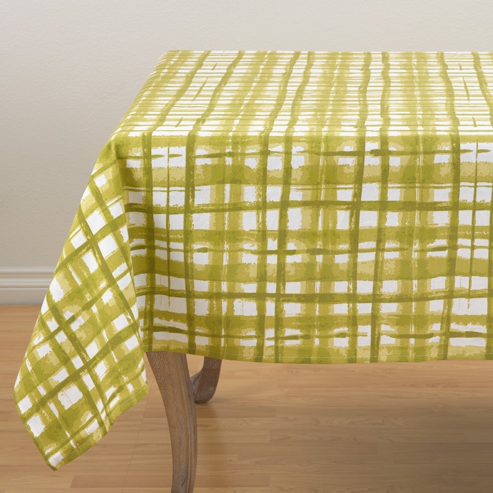 A white table cloth with green plaid pattern that is reminiscent of a watercolor painting.  Alternating wide and narrow strokes add whimsy to your tablescape.