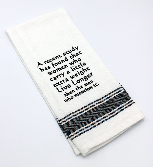 White flour sack tea towel with black printed lettering that reads "A recent study has found that women who carry a little extra weight Live Longer than the men who mention it."
