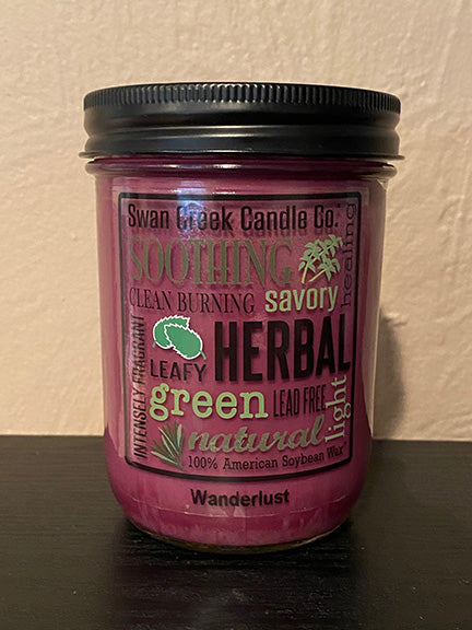 Image of a mason jar candle with burgundy colored wax.  Jar has a black lid and a clear label on the front with several words and phrases in a variety of fonts.  'Swan Creek Candle Co., Soothing, Savory, Green, Lead Free'.  Label is removable.