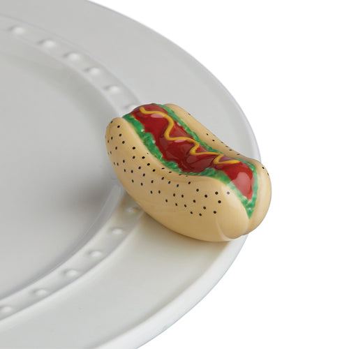 a ceramic hot dog with mustard and lettuce, inside of a seeded bun, attached to a tray.