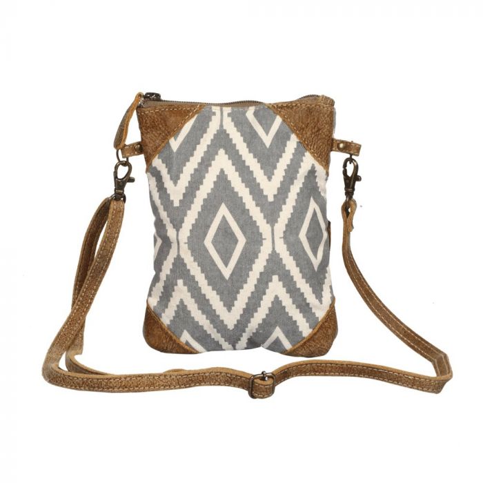 Rectangular cross body bag with a gray and off white diamond pattern, and brown leather triangular details in each of the 4 corners.  The thin brown strap is in front of the bag.