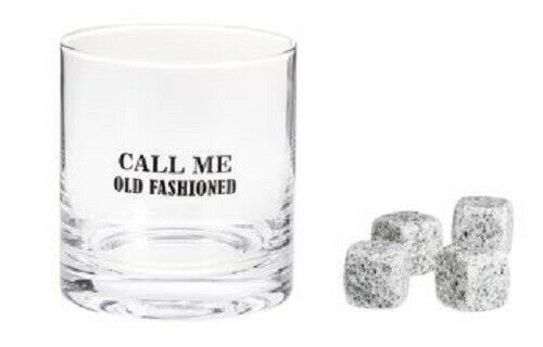 A clear rocks glass with black text on it that says 'Call Me Old Fashioned'.  Next to that glass are 4 white and black mottled stones.  