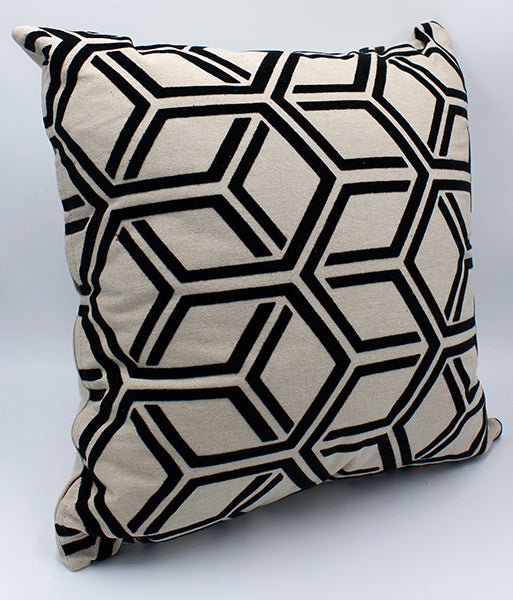 Tan pillow with black interlocking hexagon pattern sitting on a white background.