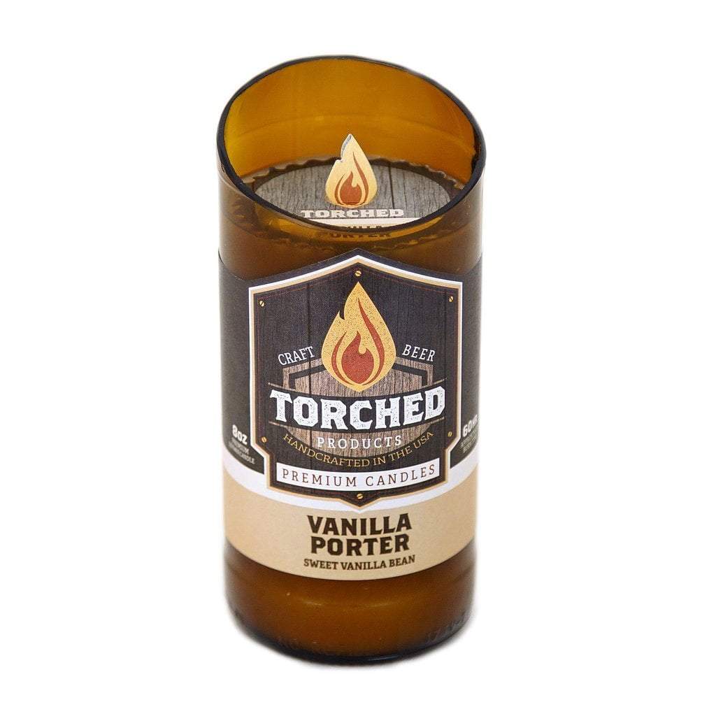 An 8 oz. beer bottle with the top cut off at a 20 degree angle.  The bottle has been filled with wax and is being sold as a candle.  The label shows an illustration of a flame and says 'Torched, craft beer premium candles.  Vanilla Porter, Sweet Vanilla Bean'